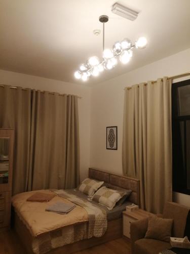 a bedroom with a bed and a chandelier at Lovely Studio in Ras al Khaimah