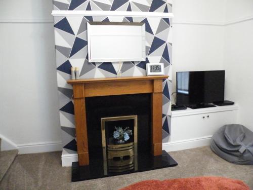 a living room with a fireplace and a tv at Family Home Near City Centre - New KING bed! in Carlisle