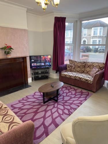 een woonkamer met een bank en een tv bij Newly renovated, spacious East London home in Seven Kings