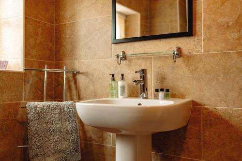 a bathroom with a white sink and a mirror at Wheatacre White Lion in Burgh Saint Peter