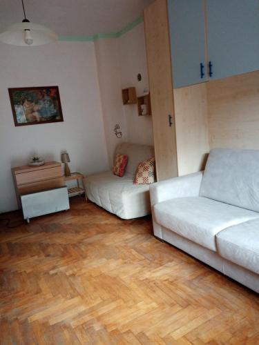 uma sala de estar com 2 sofás brancos e um piso de madeira em Guardavalle em Chiomonte