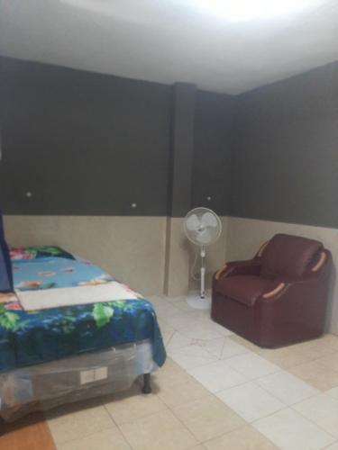 ein Schlafzimmer mit einem Bett, einem Stuhl und einem Ventilator in der Unterkunft Hotel Putin in Jinotega