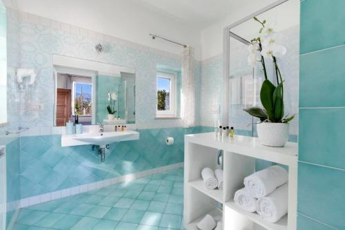 La salle de bains bleue est pourvue d'un lavabo et d'un miroir. dans l'établissement Amore Rentals - Casa Limoneto, à Sorrente