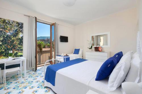 a white bedroom with a bed and a large window at Amore Rentals - Casa Limoneto in Sorrento