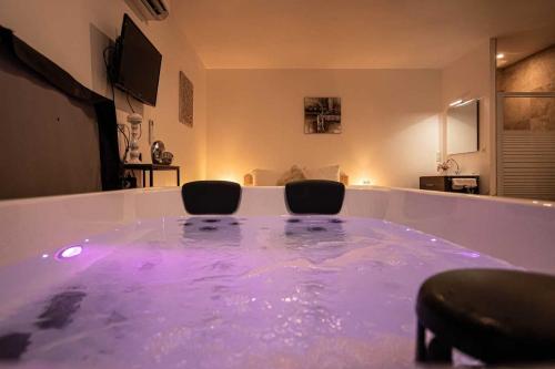 a room with a large tub filled with purple water at Gites spa de charme L ETOILE SPA in Beynac-et-Cazenac