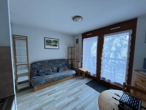 een woonkamer met een bank en een raam bij Studio pieds des pistes plein soleil in Les Contamines-Montjoie