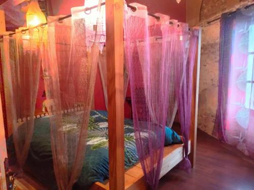 a bedroom with a bed with pink drapes at La maison du colibri 