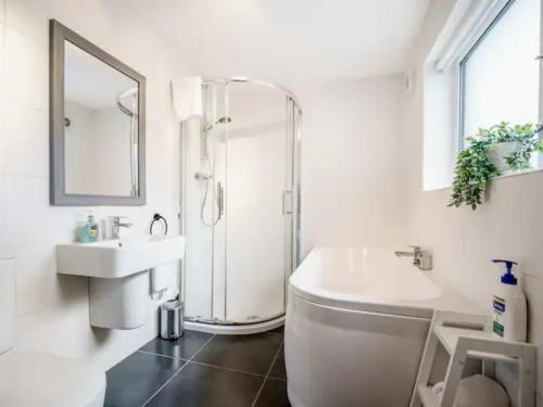 uma casa de banho branca com um chuveiro e um lavatório. em Pass the Keys Belmont Bolthole 2 Bed Bars and Eateries Abound em Belfast