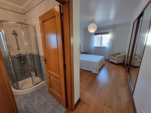 um quarto com uma cama e um chuveiro e uma casa de banho em Quinta das Rosas - Beach and Mountain apartment em Buarcos