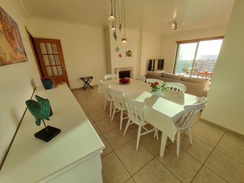 a dining room with a white table and chairs at Quinta das Rosas - Beach and Mountain apartment in Buarcos