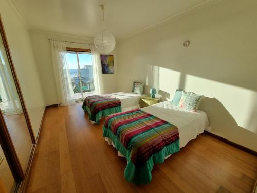 um quarto com duas camas e uma janela em Quinta das Rosas - Beach and Mountain apartment em Buarcos