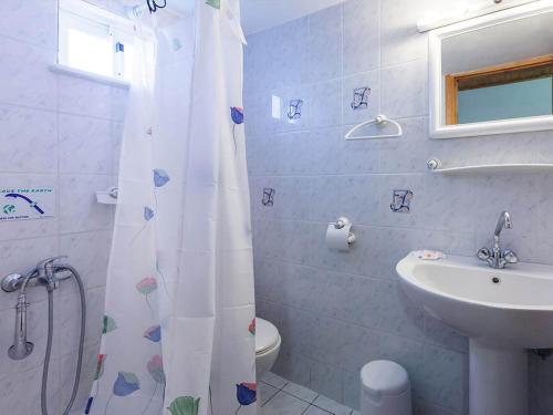 a bathroom with a sink and a toilet and a shower curtain at CottonClub Villas in Tolo
