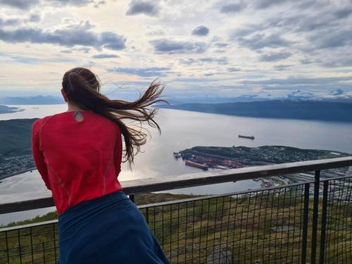 una mujer mirando sobre un cuerpo de agua en Private Mountain Apartment, en Narvik