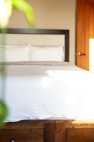 a bed with white sheets and pillows on it at Waterfront Condo in Ucluelet in Ucluelet