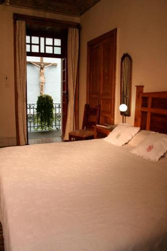 a bedroom with a bed and a cross on the window at Hotel Boutique Casa de la Palma in Puebla