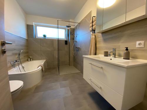een badkamer met een wastafel, een bad en een toilet bij Neu! Modern am Bowlingcenter in Werlte