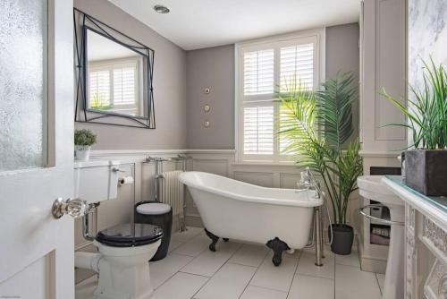 een badkamer met een wit bad en een toilet bij Villa Vita - Ideally located cottage by the sea in Deal