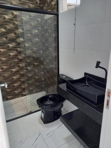 a bathroom with a black toilet and a sink at Pousada & Hotel Fazenda Segredo Das Águas in Alto Caparao