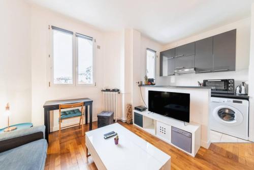 a living room with a couch a table and a tv at Appartement Rousseau F2 in Montrouge