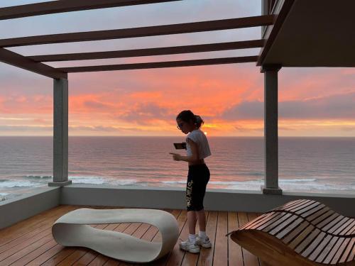 a woman standing on a balcony looking at the ocean at Feel the Ocean Design Apartment in Pataias