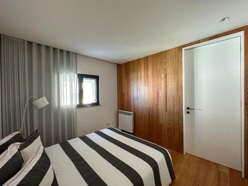 a bedroom with a black and white bed and a door at NEW! Feel the Ocean Design Apartment in Pataias