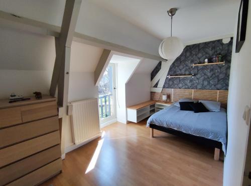 une chambre avec un lit bleu et une grande fenêtre dans l'établissement Le Chai de gandil, à Saint-Vincent-de-Cosse