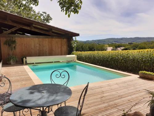 un patio avec une table et des chaises à côté d'une piscine dans l'établissement Le Chai de gandil, à Saint-Vincent-de-Cosse