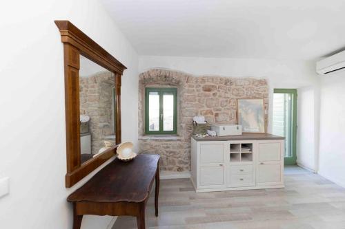 a room with a bench and a mirror and a stone wall at Villa Agora - Betina in Betina