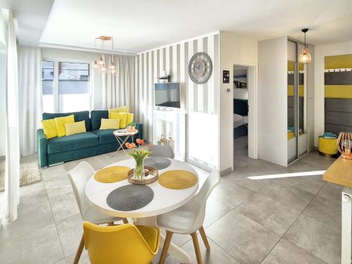 - un salon avec une table blanche et des chaises jaunes dans l'établissement Apartament Yellow Mielno, à Mielno