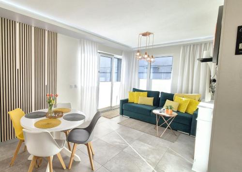 - un salon avec un canapé bleu et une table dans l'établissement Apartament Yellow Mielno, à Mielno