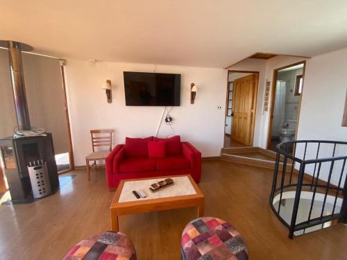 a living room with a red couch and a tv at Casa con vista al mar en Caldera in Caldera