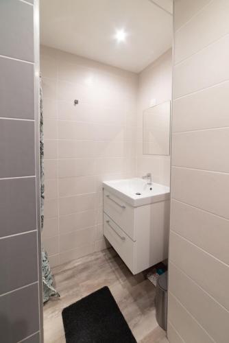 ein weißes Badezimmer mit einem Waschbecken und einem Spiegel in der Unterkunft Studio Green Groupama Lyon , Eurexpo Aréna in Meyzieu