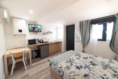 ein Schlafzimmer mit einem Bett und einem Schreibtisch sowie eine Küche in der Unterkunft Studio Green Groupama Lyon , Eurexpo Aréna in Meyzieu
