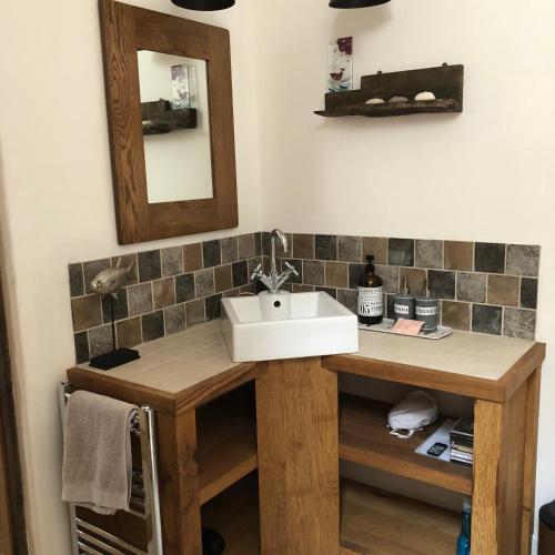 a bathroom with a sink and a mirror at Peaceful Exmoor Barn conversion with Sauna in Exford