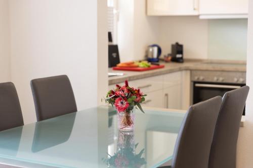 a glass table with a vase of flowers on it at Hotel Peterhof - urban lifestyle Kempten in Kempten