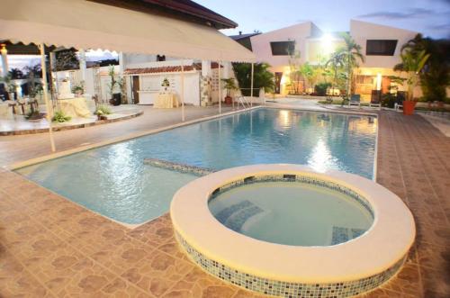 a swimming pool in a hotel with an umbrella at Hotel Tropicana Santo Domingo in La Viva