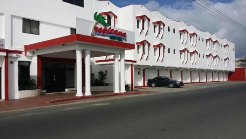 a white building with a car parked in front of it at Hotel Tropicana Santo Domingo in La Viva