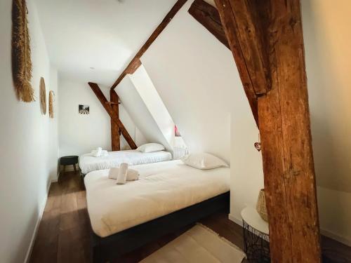 two beds in a attic room with wooden beams at Le Gite du Kaiser in Kaysersberg