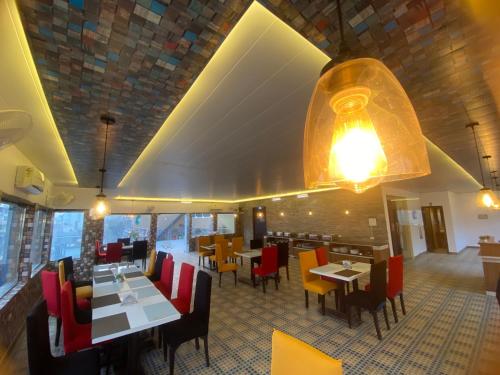 リシケーシュにあるMJ Hills Rishikeshのテーブルと椅子、照明器具が備わるレストラン