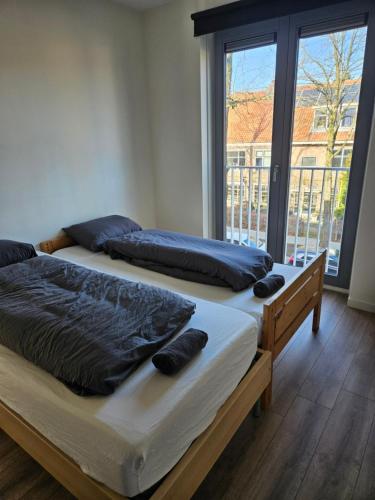 two beds in a room with a large window at Residence Dordrecht in Dordrecht