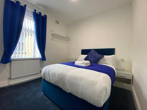 a bedroom with a blue and white bed with a window at The New Athena Hotel in Blackpool