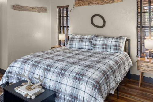 a bedroom with a bed with a plaid blanket and a mirror at Stonegate Lodge Bear's Den Kitchen, Pool, Firepit, WIFI ,Smart TVs in Eureka Springs
