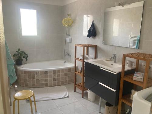 La salle de bains est pourvue d'une baignoire, d'un lavabo et d'une baignoire. dans l'établissement La maison aux palmiers, à Arpaillargues-et-Aureillac