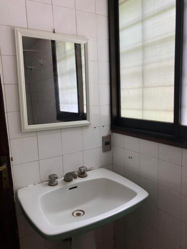 een witte wastafel in een badkamer met 2 ramen bij Casa Bosquemar in Concón