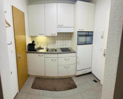 a small kitchen with white cabinets and a sink at Casa Carvalho in Lucerne