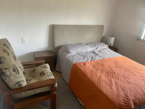 a small bedroom with a bed and a chair at Casa en colonia del sacramento in Colonia del Sacramento