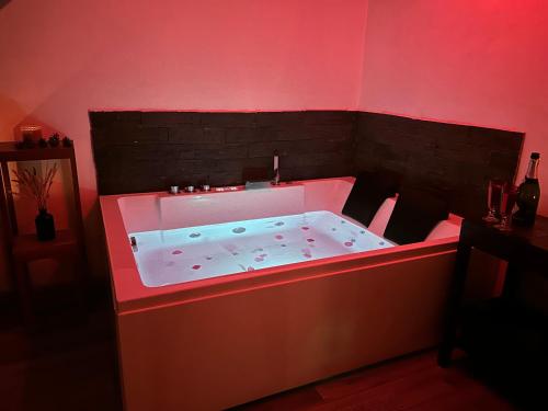a hot tub in a room with red lighting at Maison à la campagne avec piscine privée et balnéo in Sendets