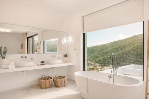 a white bathroom with a tub and a large window at Kefalonia Grande Horizon in Ayia Evfimia