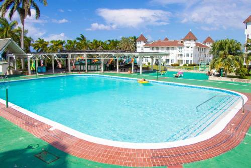 a large swimming pool in a resort with palm trees at Malibu Ocean View Studio in Montego Bay