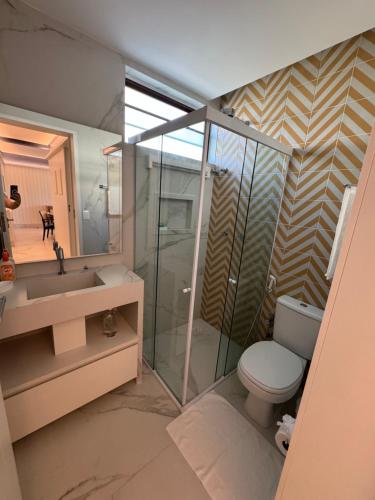 een badkamer met een toilet, een wastafel en een spiegel bij Flat+deck ao lado da igrejinha in Praia dos Carneiros